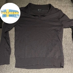 Svart merinoull tröja från Riley - Snygg svart långärmad tröja från Riley med en stilren design. Perfekt för en avslappnad look. Tröjan har en klassisk krage och är tillverkad i av merinoull för extra komfort.