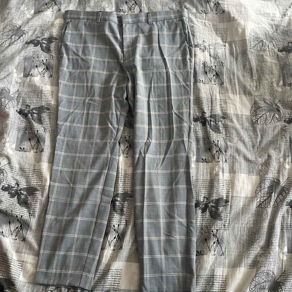 Snygga grå kostymbyxor med ett klassiskt rutmönster. De har en rak passform och är perfekta för en stilren look. Byxorna har hällor för bälte och knappar bak.. Farkut & Housut.