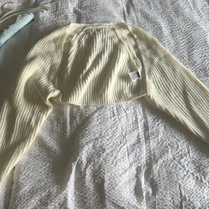 Vit ribbad bolerotopp - Säljer en stilren vit ribbad bolerotopp med långa ärmar. Perfekt för att lägga till en extra touch till din outfit. Passar bra över en klänning eller topp för en chic look.