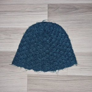 Grön stickad mössa - Säljer en mysig grön stickad mössa. Mössan har en enkel design som passar till det mesta. Mått: ca 25 cm i bredd och 28 cm i höjd.