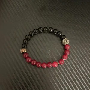 Svart och rött armband med dödskalle - Coolt armband med svarta och röda pärlor. Det har en unik dödskalle-detalj i metall som ger en edgy look. Perfekt för att ge din outfit lite extra attityd!