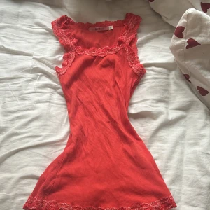 Röd ribbad linne från RoseBud - Säljer en superfin röd ribbad linne från RoseBud i storlek S. Den har vackra spetsdetaljer vid ärmslut och halsringning, vilket ger en romantisk touch. Perfekt för sommardagar eller som ett lager under en kofta. Passar både till vardags och fest! Pris går alltid o diskutera 💗💗