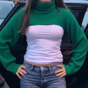 Grön ribbad croppad polotröja - Säljer en supercool grön ribbad polotröja som är croppad. Perfekt för lager-på-lager-stil! Den har långa ärmar och en härlig grön färg som verkligen poppar. Passar perfekt till jeans eller kjol för en trendig look. Perfekt för höst och vår!