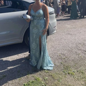 Ljus blå balklänning  - Använd 1 gång super fin glittrar mycket, den är köpt för 1636kr från ZAPAKA.se Storlek 40 den passar en person med byst 93cm, midja 75cm och höft 101cm den går också att justera i ryggen och har inbyggd bh.