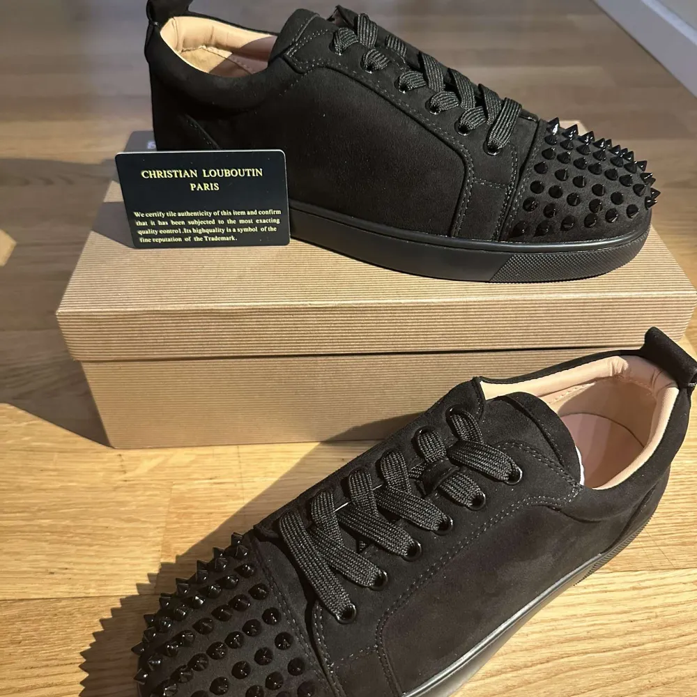 Snygga svarta sneakers i mocka från Christian Louboutin med coola nitar på tån. De har en klassisk röd sula och snörning. Perfekta för att ge din outfit en edgy touch. Skorna är i nytt skick och kommer i originalförpackning. Storlek 41 . Skor.