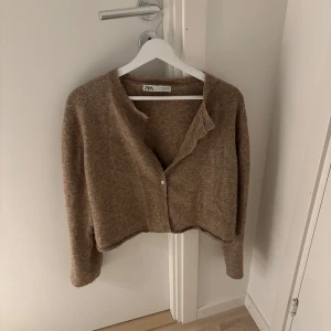 Beige kofta från Zara - Säljer en superfin beige kofta från Zara i storlek S. Den är croppad och har en mysig, stickad känsla. Perfekt för höst och vår! Koftan har långa ärmar och knappar framtill. Den är i mycket bra skick och passar perfekt till både vardag och fest. 🧡