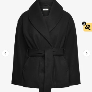 Svart kappa  - Säljer en stilren svart kappa i mycket bra skick. Den har en elegant omlott-design med ett bälte i midjan för en snygg passform. Perfekt för höst och vår, och funkar lika bra till vardags som till fest. Kappan har långa ärmar och är gjord i ett mjukt material som känns skönt mot huden.