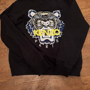 Säljer en äkta svart sweatshirt från Kenzo med ett coolt broderat tigerhuvud och texten 'KENZO PARIS' på framsidan. Tröjan har långa ärmar och är i mycket bra. Vet inte priset på den här. 