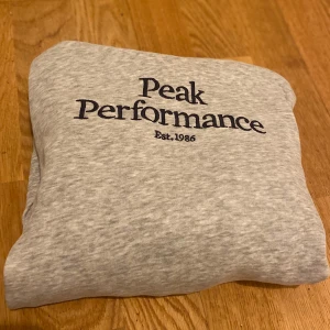 Grå hoodie från Peak Performance - Säljer en snygg och bekväm grå hoodie från Peak Performance. Den har en klassisk design med logga på bröstet och en praktisk magficka. Perfekt för både vardag och chill. Huvan är mjuk och skön, och materialet känns riktigt bra mot huden. Passar perfekt till kallare dagar! Kom gärna med frågor eller prisförslag!😊🤝