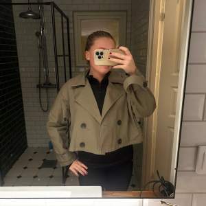 Säljer en superfin beige croppad trenchcoat med stora knappar. Perfekt för hösten och våren! Jackan har en loose passform och långa ärmar. Den är både stilren och trendig, perfekt för att lyfta vilken outfit som helst. 🧥✨