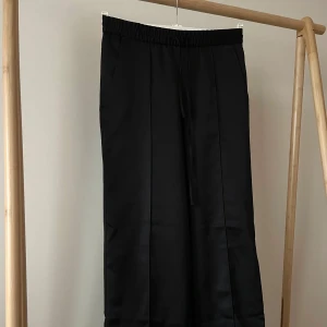 Glansig rak kostymbyxa - Ett par raka kostymbyxor i lite glansigt material, en snygg söm på framsidan🥰 Lite noppriga vid benslutet.