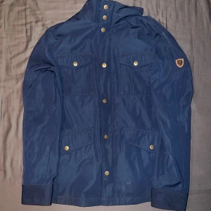 Bondelid fieldjacka  - Säljer en snygg blå fieldjacka från Bondelid i storlek S. Jackan har knappar framtill samt på fickorna. Perfekt för höst och vår med sin stilrena design och praktiska fickor. Passar både till vardags och lite finare tillfällen. Inga defekter finns och hör av er vid frågor!