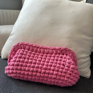 Rosa virkad väska - Säljer en superfin rosa virkad väska som är perfekt för att hålla ordning på småsaker. Den är handgjord med ett tjockt garn som ger en mysig och unik känsla. Perfekt som en liten handväska eller necessär. 👜✨