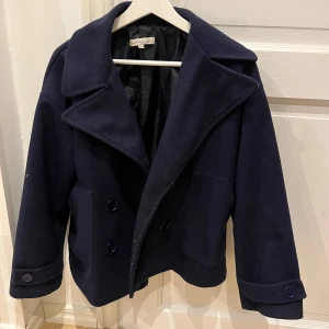 Marinblå designbysi kappa - Säljer en snygg marinblå kappa från designbysi, med dubbelknäppning och bred krage. Perfekt för höst, vår och vinter! Den har långa ärmar och en stilren design som passar både till vardags och fest. Den är i jätte bra skick!💞