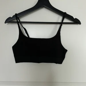 Svart ärmlös linnetopp - Snygg och enkel svart linnetopp i ett mjukt material. Perfekt för sommardagar eller som basplagg under en jacka. Toppen har smala axelband och en tight passform som framhäver figuren.