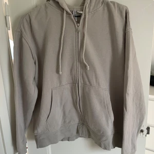 Beige zip hoodie från H&M  - Säljer en superbekväm beige hoodie från H&M Divided i storlek M. Den har en dragkedja framtill och en justerbar huva med snören. Perfekt för en avslappnad stil och passar till alla årstider. Använd men i bra skick!🤍