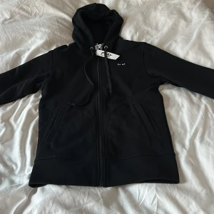 Comme des garcons svart hoodie (passar dig som är mellan 160-170) - Hej! jag säljer comme des garcons hoodie,Nypriset ligger runt 3000 kr, fick den i födelsedagspresent men den var för liten för mig.Som du ser så har den alla tags kvar och är aldrig använd! Skriv vid några funderingar priset är inte hugget i sten !