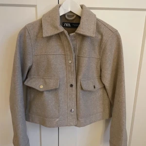 Beige jacka från Zara - Säljer en snygg slutsåld beige jacka från Zara i mycket bra skick. Den har en klassisk krage och knappar framtill. Perfekt för höst och vår, med en stilren look som passar till det mesta. Jackan har långa ärmar och praktiska fickor med lock. Nypris 400kr. Kommer inte till användning!🤍🤍