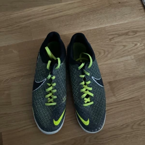 Nike elastico futsal - Säljer ett par Nike Mercurial fotbollsskor i mycket bra skick. De är grå med neongula detaljer och snörning. Perfekta för inomhusfotboll med en slitstark sula. Skorna har en snygg och modern design med den klassiska Nike-loggan på sidan.