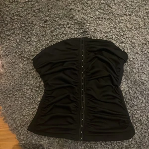 Svart korsett/tubtopp - Snygg svart korsett liknande tubtopp i ett stretchigt material som är figursittande. Aldrig använd eftersom fel storlek💕