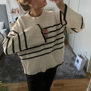 Randig stickad tröja i beige och svart - Säljer en supermysig stickad tröja i beige med svarta ränder. Den har en lite oversized passform, perfekt för höst och vinter. Tröjan är i mycket bra skick och använd fåtal gånger. Storlek xs. (Den är lite skrynklig då den legat nerpackad!!) 💓💓💓