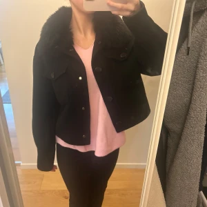 Meotine liknande jacka  - Säljer en snygg svart jacka med pälsdetalj på kragen. Jackan är croppad och har långa ärmar, perfekt för höst och vinter. Den har knappar framtill och en stilren design som passar både till vardags och fest. Superfin och i  sparsamt använd, dock en knapp där första lagret håller på att flagna lite💕