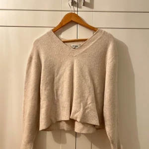 Beige stickad tröja från Weekday - Mysig beige stickad tröja från Weekday i mycket bra skick. Den har en v-ringad hals och långa ärmar, perfekt för höst och vinter. Tröjan är ribbad vid ärmslut och nederkant vilket ger en snygg detalj. Superfin att matcha med jeans eller kjol! Använt då o då men i bra skick.