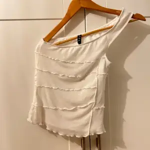 Säljer en superfin vit oneshoulder topp från motel rocks. Den har ett snyggt mönster och är gjord i ett lätt och luftigt material, perfekt för sommardagar. Två lagen en med mesh och en underdel med satin liknande material. Toppen är i mycket bra skick och passar perfekt till både vardag och fest! Aldrig använt men utan prislapp!