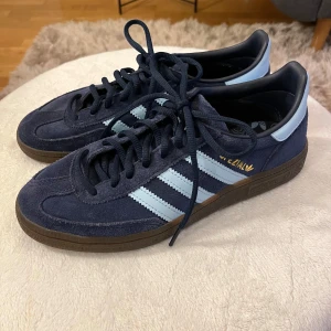Adidas sneakers i mörkblå mocka - Snygga Adidas sneakers i mörkblå mocka med ljusblå detaljer och klassiska tre ränder. Har haft dem ett tag men bara använt 5-7 gånger, har ej lådan dem kom i kvar💗