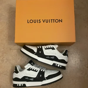 Svartvita sneakers från Louis Vuitton - Snygga svartvita sneakers från Louis Vuitton med märkets logotyp på sidan och sulan. Skorna har snörning och en unik design med #54 på hälen. Perfekta för den stilmedvetna.