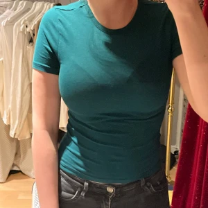 Grön tight t-shirt - Säljer en stilren grön t-shirt med korta ärmar. T-shirten har en tight passform och är perfekt för en avslappnad look.