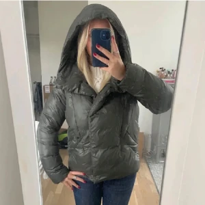 Grön pufferjacka med huva - Säljer en grön pufferjacka med huva. Jackan har en quiltad design och långa ärmar, perfekt för kyligare dagar. Den är både stilren och praktisk, idealisk för höst och vinter. Bara att dm:a vid frågor eller funderingar!💞❄️Pris kan diskuteras vid snabb affär!
