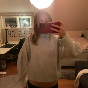 Grå stickad tröja - Säljer en mysig grå stickad tröja med långa ärmar. Perfekt för kyligare dagar och ger en avslappnad look.