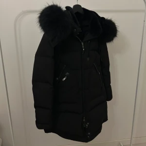 Svart CEDRICO Jacka med pälshuva - Snygg svart dunjacka med fluffig pälshuva och dragkedja framtill. Jackan har en stilren design med praktiska fickor och är perfekt för kyliga dagar. Pris kan diskuteras 