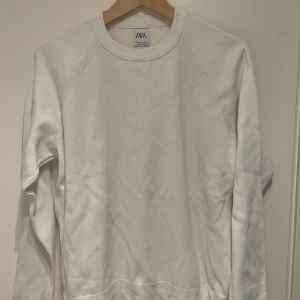 Vit tröja från Zara - Säljer en stilren vit tröja från Zara. Tröjan har en klassisk design med rund hals och långa ärmar. Perfekt för en avslappnad look.