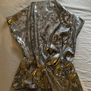 Silvrig  topp från Zara - Snygg silver topp från Zara. Toppen har korta ärmar och en dragkedja i ryggen. Perfekt för en festlig kväll!🪩✨