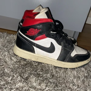 Nike Air Jordans i svart, vitt och rött - Säljer ett par klassiska Nike Air Jordans i svart, vitt och rött. Skorna har snörning och den ikoniska Air Jordan-loggan på sidan. Perfekta för höst vinter o sommar tiderna! Priset kan diskuteras. Hör av er vid frågor! De är storlek 35,5 men passar även 36! Köpt på footlocker 2022 för 1149kr