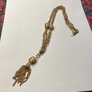  EMMONS Guldhalsband med tofsdetalj - Elegant vintage guldhalsband Emmons från USA med intrikata detaljer och en dekorativ tofs. Halsbandet har flera kedjor och utsmyckade pärlor som ger en lyxig känsla. Perfekt för att lyfta vilken outfit som helst.