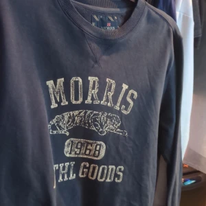 Mörkblå sweatshirt från Morris - Säljer en mörkblå sweatshirt från Morris med tryck framtill. Tröjan har långa ärmar och rund halsringning. Perfekt för en avslappnad stil.