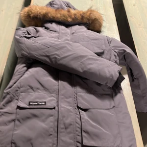 Grå parkajacka med pälsdetalj - Snygg grå parkajacka från Classic Norway med en mysig pälsdetalj på huvan. Jackan har långa ärmar och praktiska fickor framtill. Perfekt för kyliga dagar.