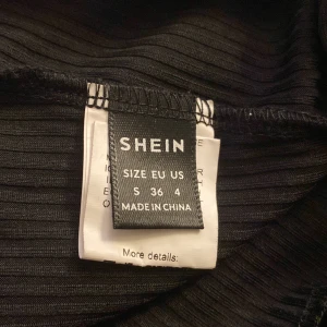 Svart ribbad kofta från Shein - Säljer en svart ribbad kofta från Shein i storlek S. Koftan har en v-ringning och knappar framtill. Den är croppad och har långa ärmar, perfekt för en stilren look.