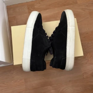 Svarta sneakers med vit sula/Axel arigato  - Snygga svarta sneakers med vit sula och snörning. Perfekta för en avslappnad stil. Tillverkade i mocka för en lyxig känsla. Pris kan diskuteras vid snabb försäljning!!