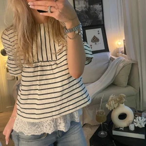 Randig topp från Tommy Hilfiger - Snygg randig topp från Tommy Hilfiger i vitt och marinblått. Toppen har trekvartsärm. Perfekt för en avslappnad stil med en touch av elegans.