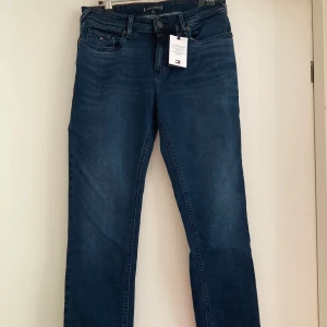 Mörkblå jeans från Tommy Hilfiger - Nya och oanvända blåsvarta  jeans från Tommy Hilfiger med klassisk femficksdesign. Modell: Scanton Slim fit stretch , storlek 164cm.  Perfekta för en stilren look. Märkeslogga på bakfickan. 