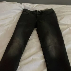 Svarta jeans från Jack & Jones slim fit - Snygga svarta jeans från Jack & Jones med en klassisk design. De har en knappgylf och är perfekta för en stilren look. Passar bra till både vardag och mer uppklädda tillfällen.