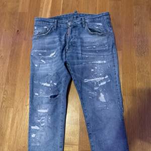 Säljer ett par blå Dsquared2 jeans med slitna detaljer och en cool, distressed look. Har använt dom en gång den är perfekt 
