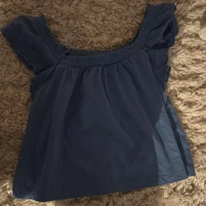 Blå topp från Ralph Lauren - Säljer en blå topp från Ralph Lauren med spetsdetaljer på axlarna. 