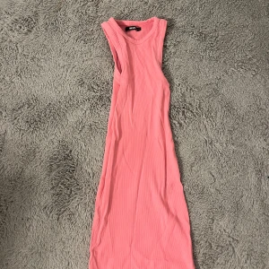 Rosa ribbad klänning från Bik Bok - Snygg rosa ribbad klänning från Bik Bok i ärmlös design. Perfekt för en stilren look med sin enkla och eleganta form. Klänningen är i en mjuk och bekväm kvalitet.