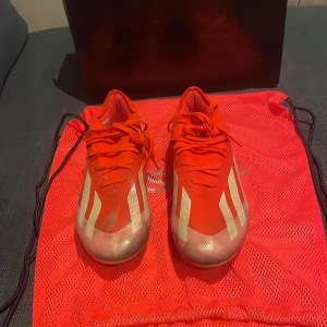 Adidas Crazyfast elite Fg - Snygga röda fotbollsskor från Adidas med vita detaljer och snörning. Perfekta för fotbollsplanen med en stilren design och bra passform.