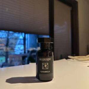 Parfym Le Couvent Ilhabela - Elegant parfymflaska från Le Couvent med doften Ilhabela. Flaskan är svart och har en stilren design med en fyrkantig kork. Perfekt för den som söker en sofistikerad och unik doftupplevelse.